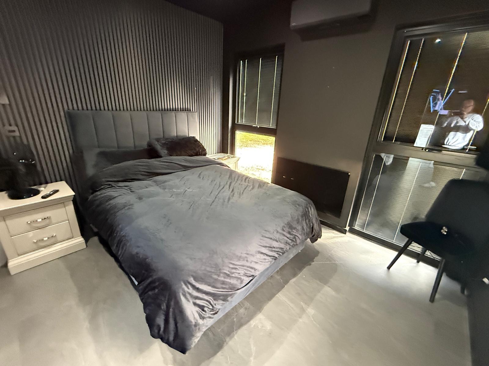 Double bedroom with panelled feature wall, air conditioning and integrated blinds