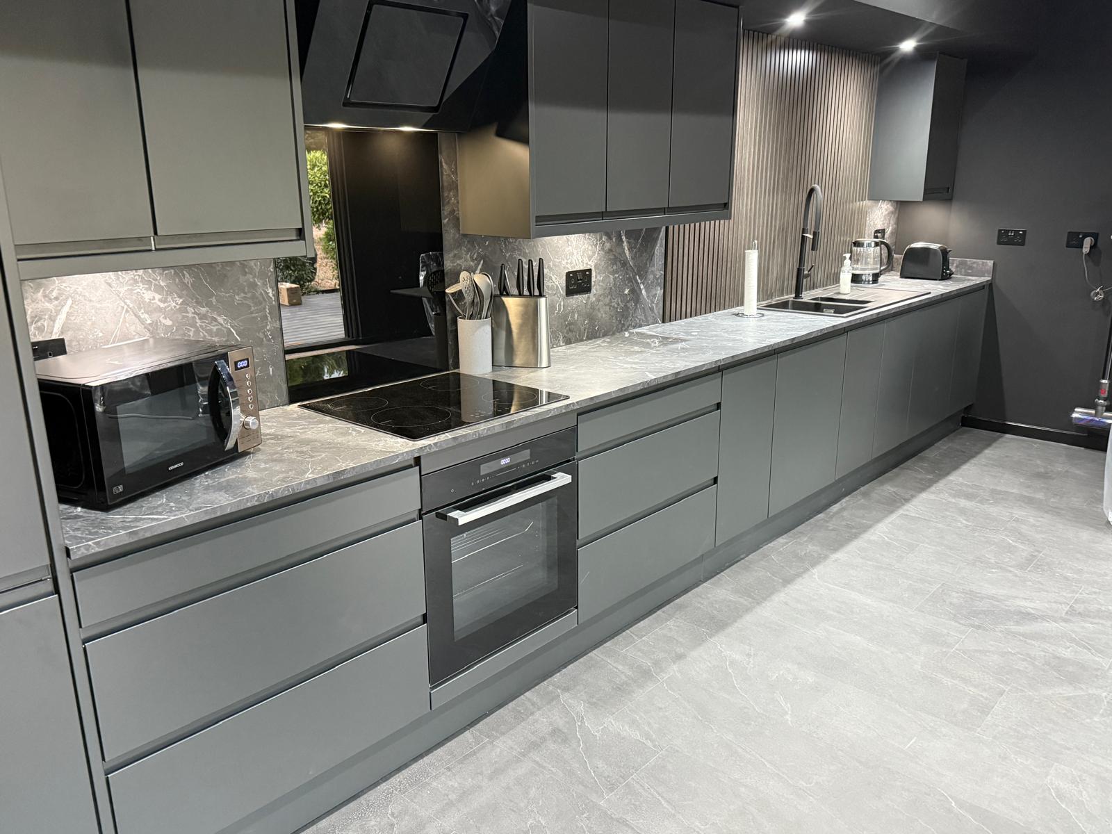 Fully fitted kitchen with graphite handleless units and marble-effect worktops
