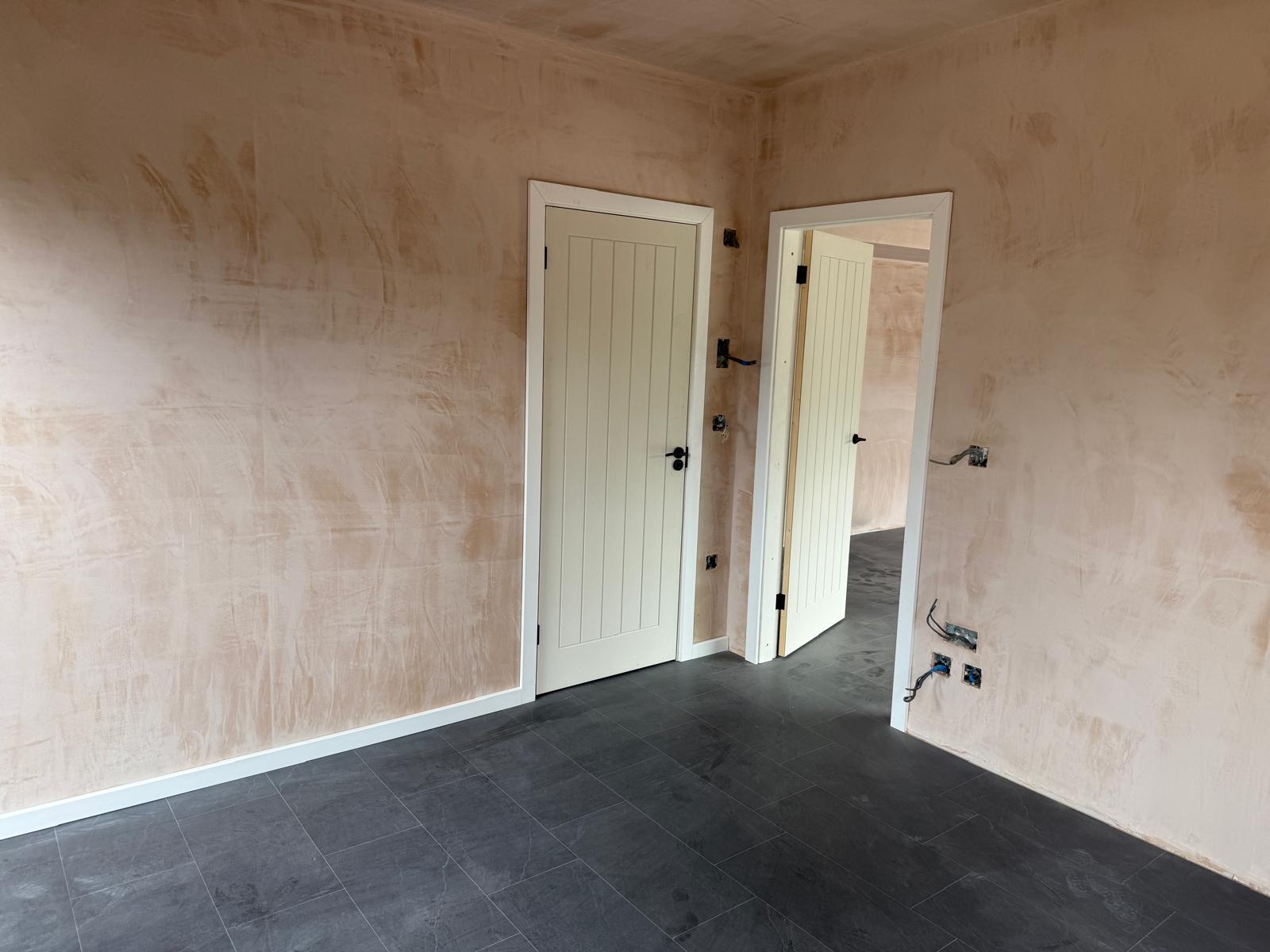Plastered bedroom with slate tiled flooring and internal doors